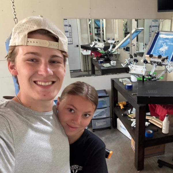 Two people standing in a room with shelves and equipment.